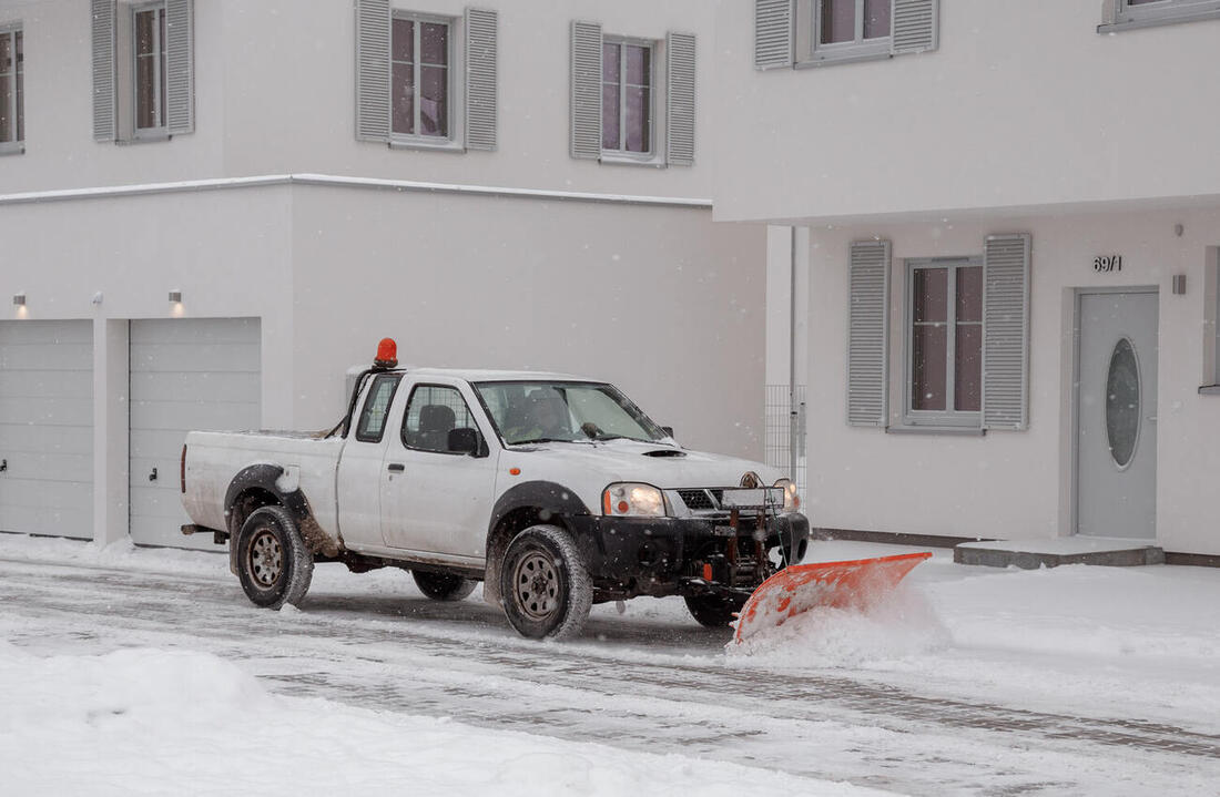 Pickup mit Schneeschild räumt eine Einfahrt bei Schneefall